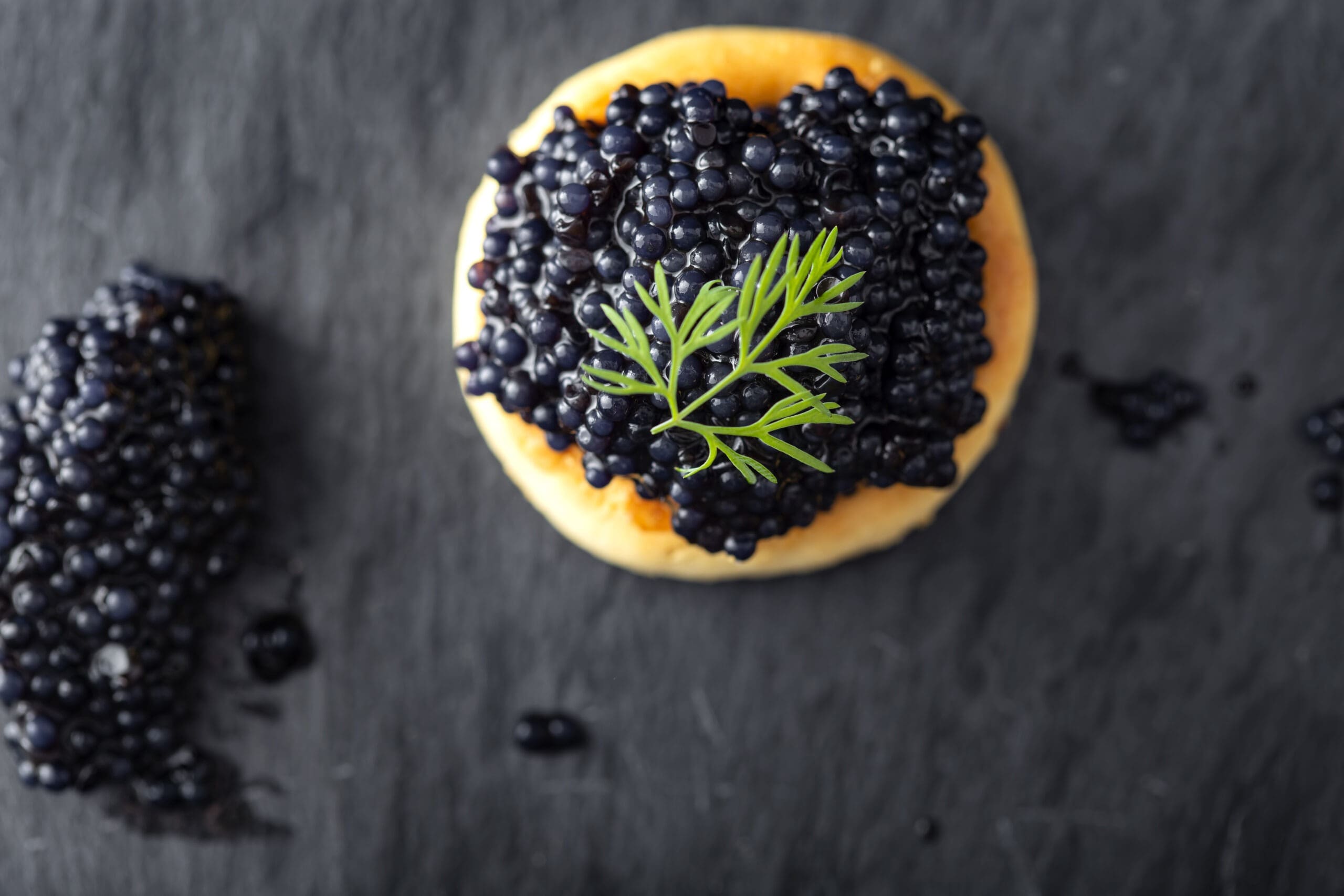 blinis with caviar on dark surface