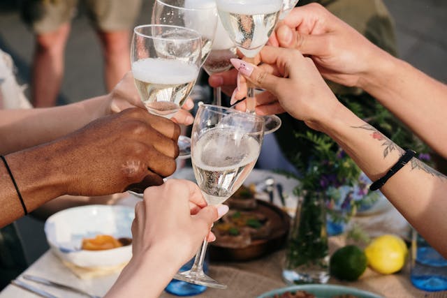 group of people cheers wine glasses at table