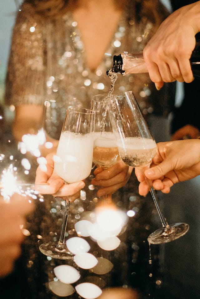 person pouring Champagne into glass flutes