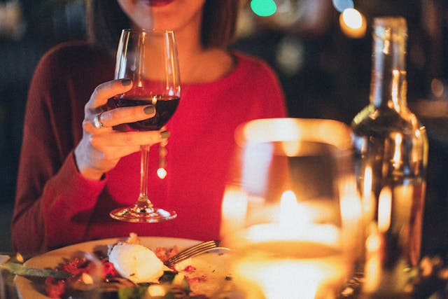 woman holding wine glass at dinner table