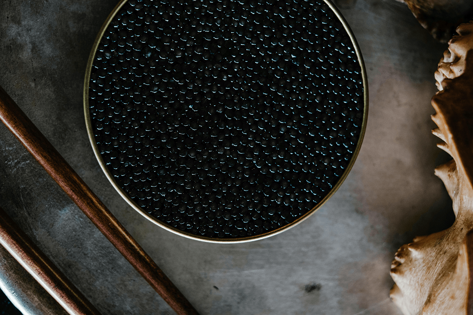Black American caviar served in a tin with chopsticks
