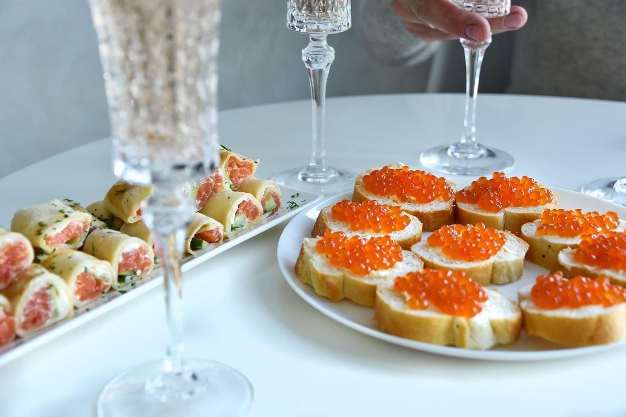 orange-red caviar on toast, Champagne, and appetizers on table