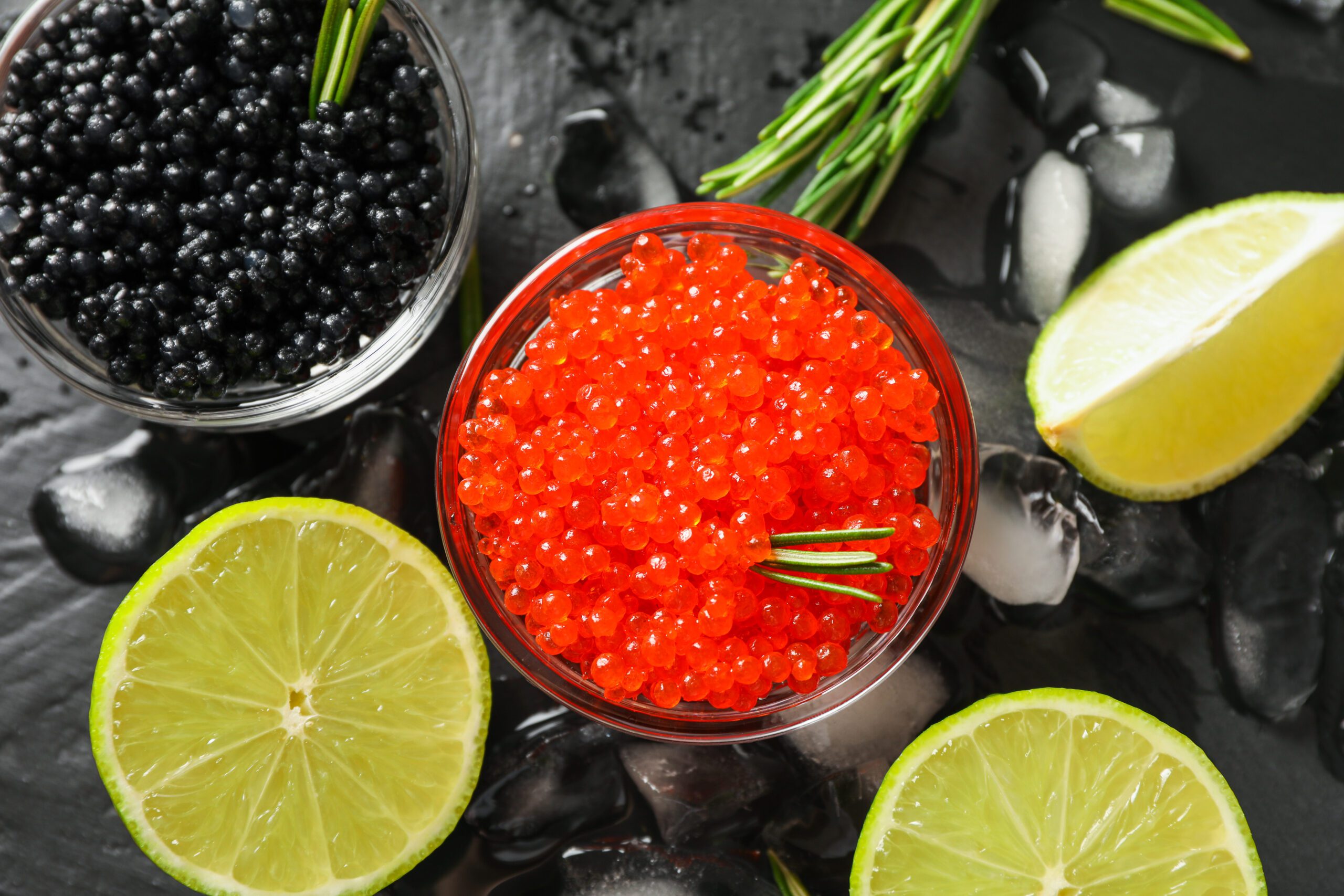 caviar and lemon wedges on dark surface