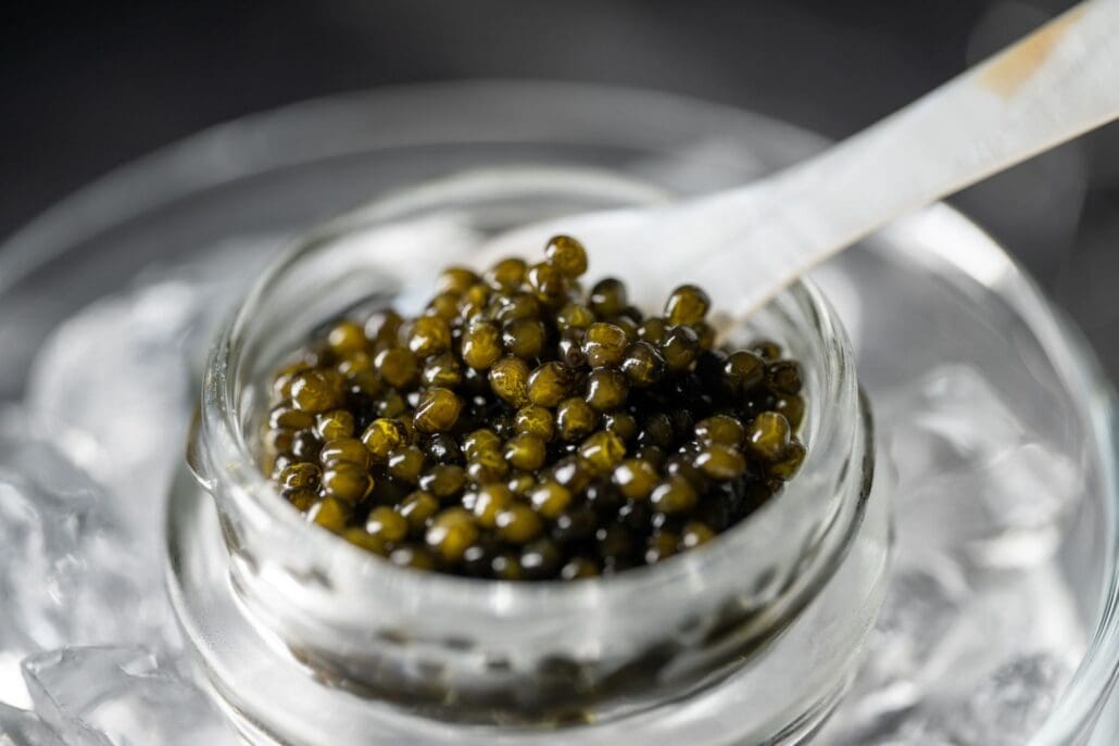 Osetra caviar in a glass jar with a mother-of-pearl spoon