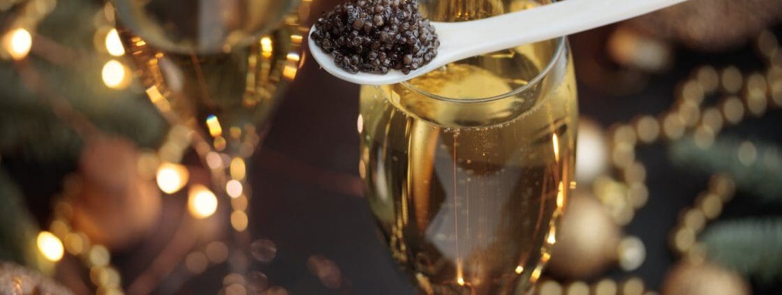 A mother-of-pearl spoon of caviar on a Champagne flute