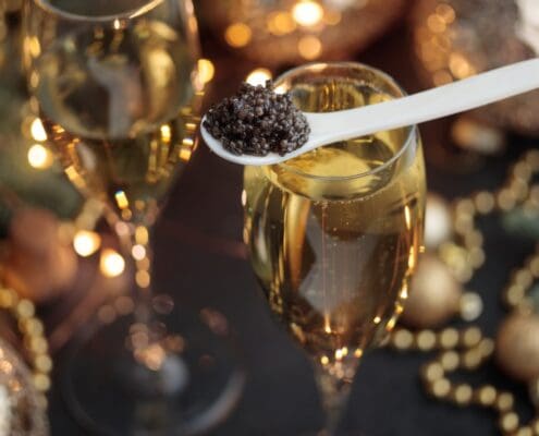 A mother-of-pearl spoon of caviar on a Champagne flute